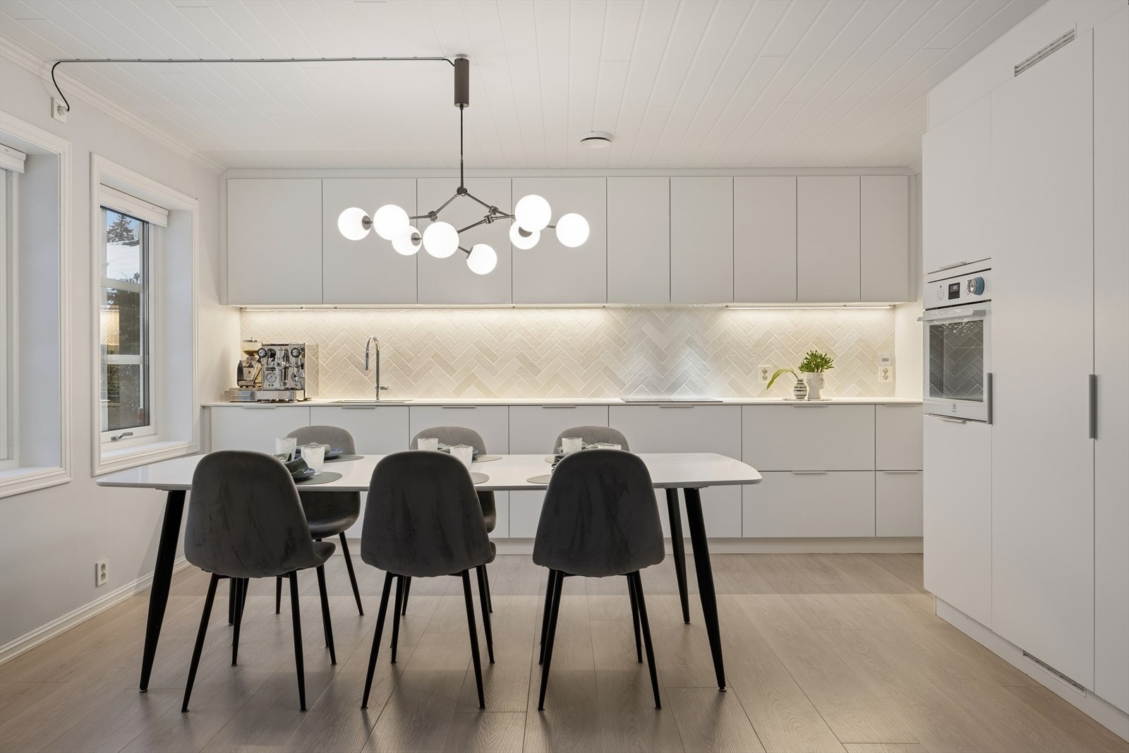 Kjøkkeninnredningen har hvite, glatte fronter og hvit laminert benkeplate med nedfelt kjøkkenkum. Galleribilde