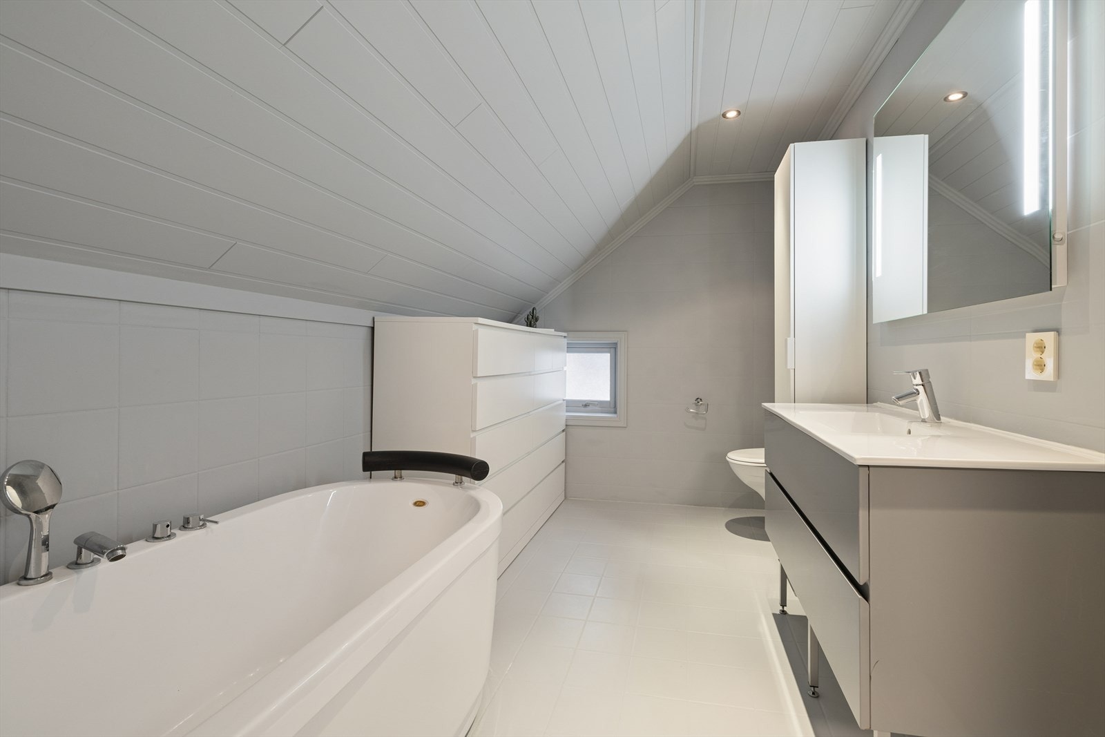 Innredningen består av baderomsinnredning med heldekkende servantplate, speil med integrert belysning, vegghengt toalett og et badekar. Galleribilde