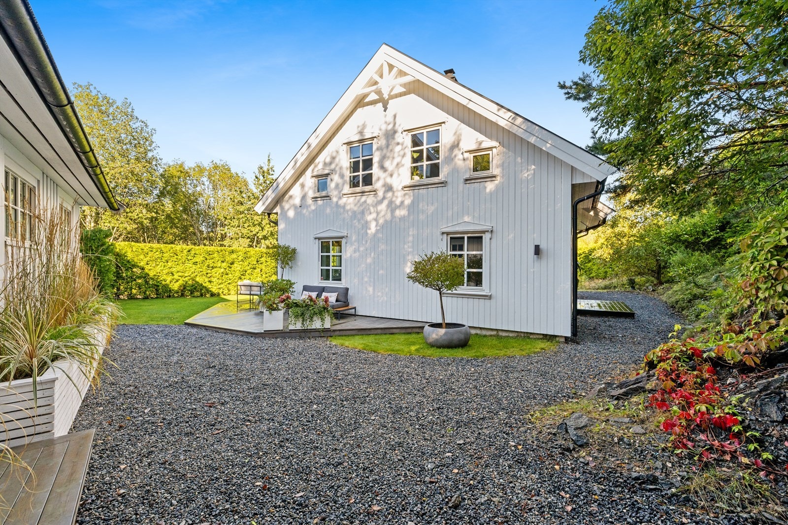 Tomten er pent opparbeidet med gruslagte veier, og grøntarealer med busker og blomster. Galleribilde