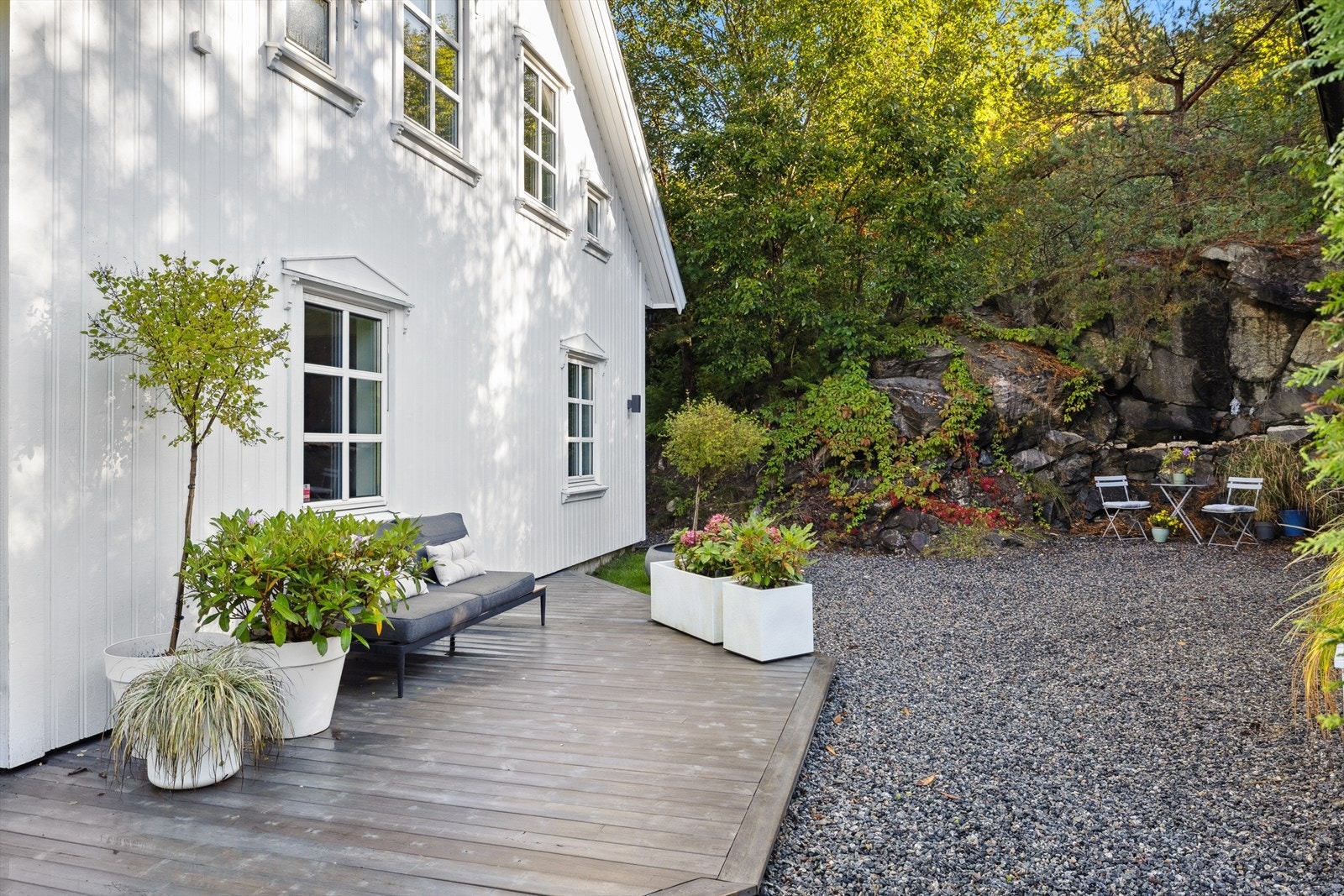 Det er også en lun sitteplass på gruslagt område ved fjellveggen, som skaper en naturlig og skjermet uteplass med et flott bakteppe av natur. Galleribilde