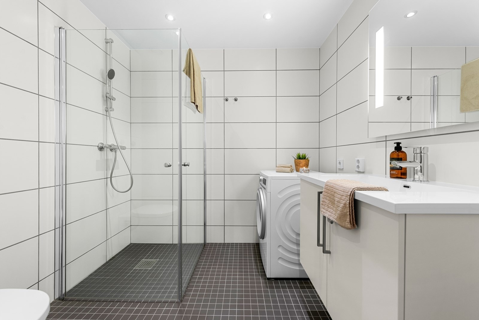 Delikat og flislagt bad med varme i gulv på 4,3m². Baderomsinnredning fra HTH. Galleribilde