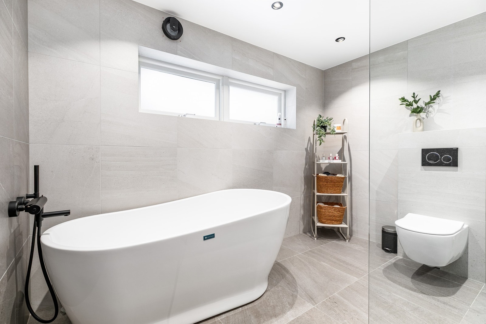 Storformat fliser på gulv og vegger skaper helhet. Himlingens innfelte spotter kan dimmes. Galleribilde