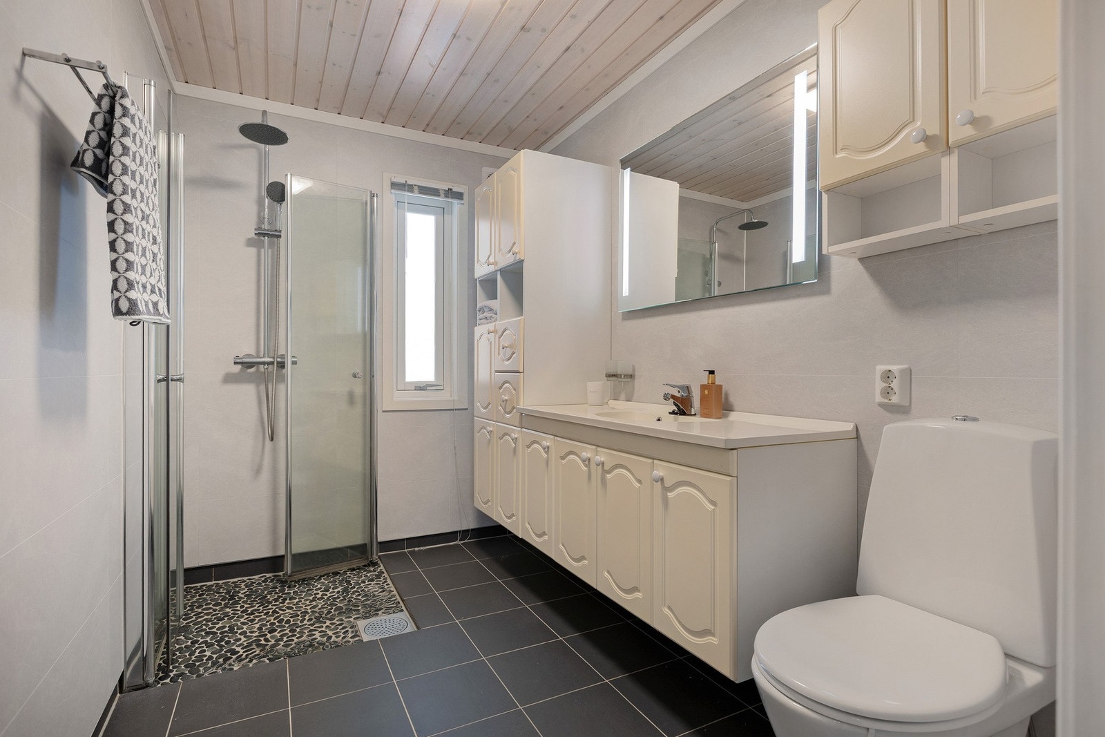 Bad/wc, innredning med mye skapplass, speil med belysning, dusjhjørne og toalett Galleribilde