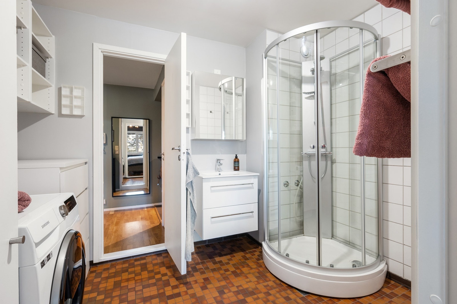 Baderommet har flislagt gulv med varmekabler, dusjkabinett og opplegg for vaskemaskin. Galleribilde