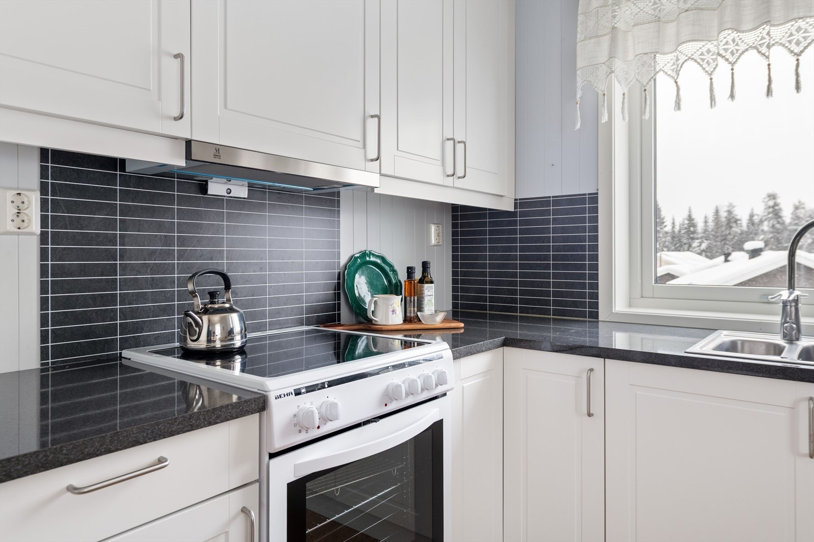 Lyst og innbydende kjøkken med laminert benkeplate, profilerte fronter og plass til frittstående komfyr. Galleribilde