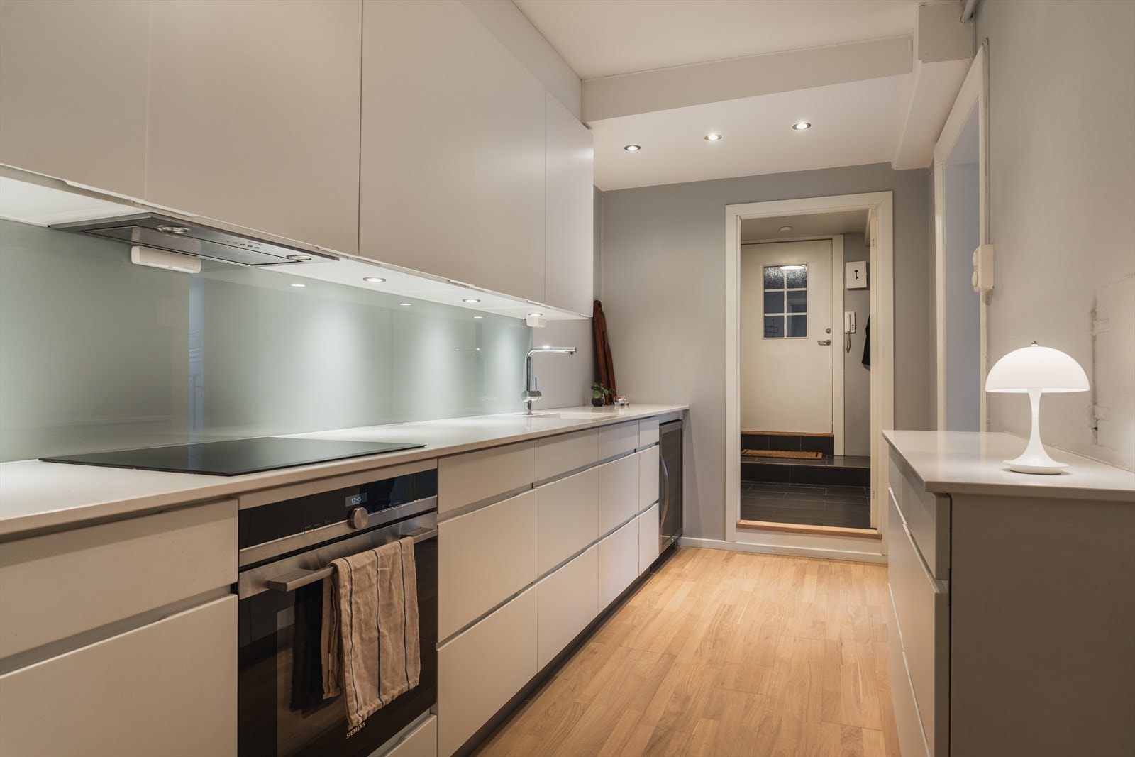 Kjøkkenet er utstyrt med integrerte hvitevarer fra Siemens, herunder induksjonstopp, stekeovn, oppvaskmaskin samt kjøleskap og fryseskap plassert under benk. Galleribilde