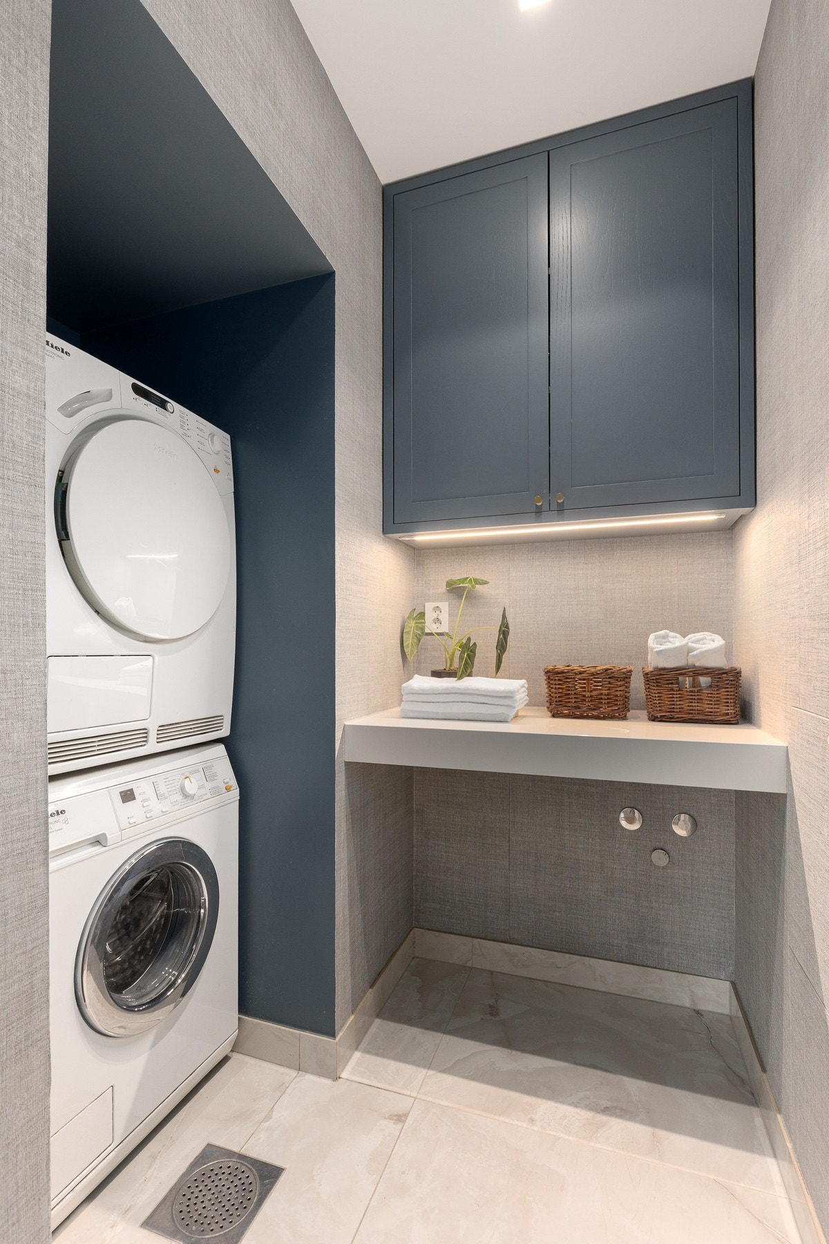 Vaskerommet er praktisk og funksjonelt utformet med nisje til vaskemaskin og tørketrommel, komplettert med benk og overskap for god lagringsplass Galleribilde