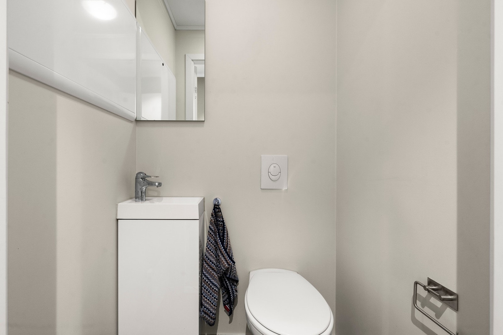 Entreen gir direkte tilgang til gjestetoalettet. Innredet med håndvask, speil, panelovn og veggmontert vannklosett. Balansert ventilasjon. Galleribilde