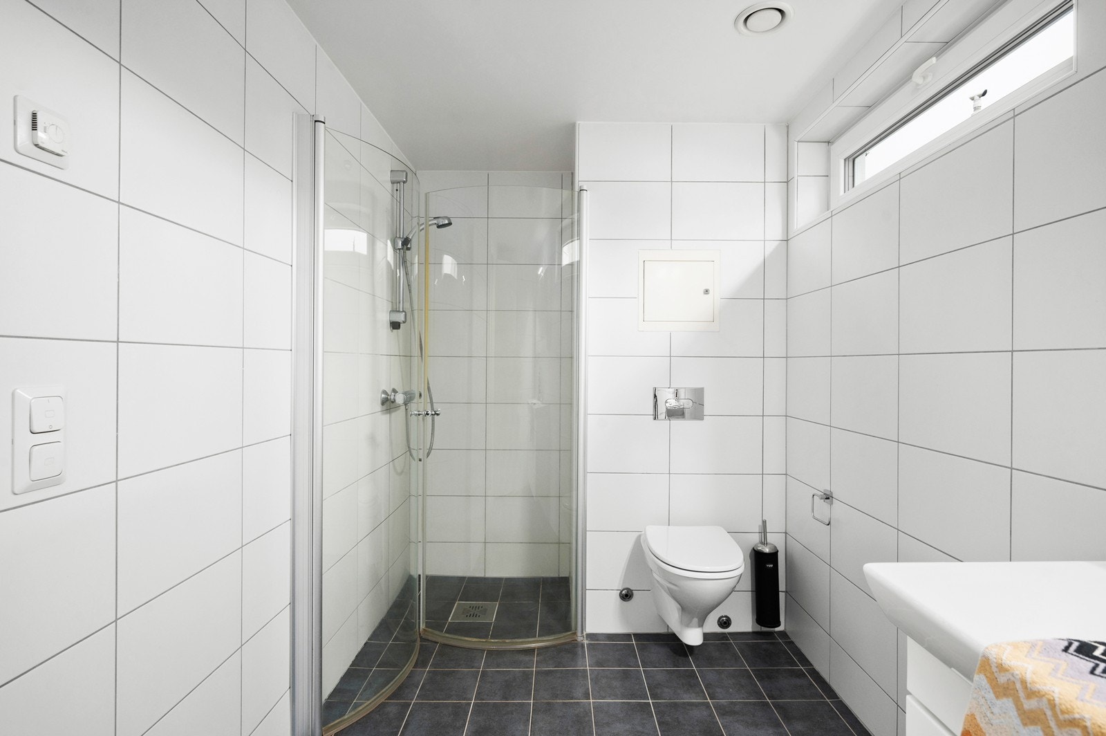 Flislagt bad består av servant med innredning, hjørnedusj med innfeltbare dører og vegghengt klosett Galleribilde