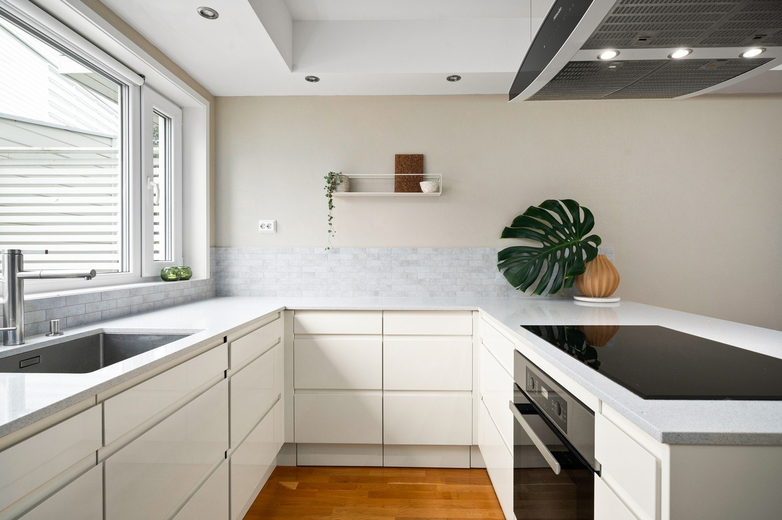 Praktisk innredet kjøkken med gode arbeidssoner og et hyggelig utsyn mot hage og lekeplass Galleribilde