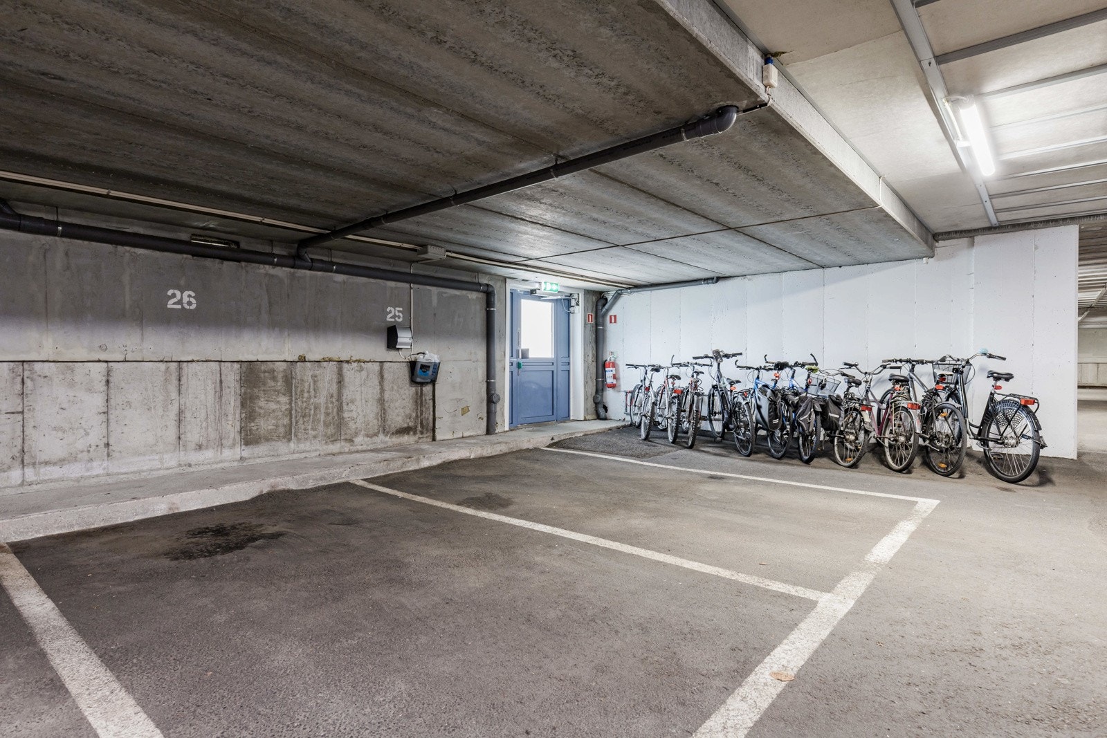 Parkeringsanlegg med faste plasser, elbillader og felles sykkelparkering i tilknytning til utgang. Galleribilde