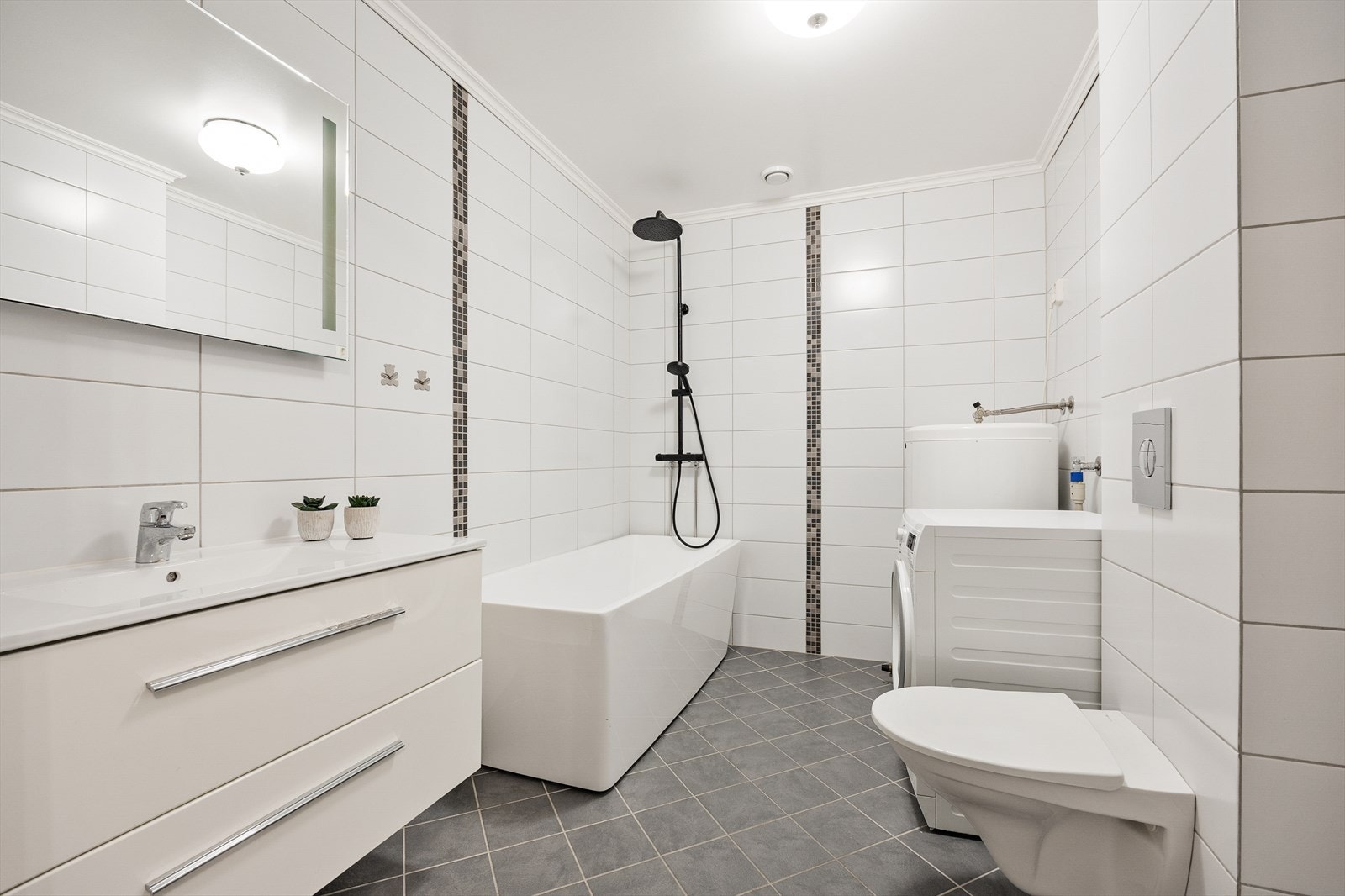 Det romslige hovedbadet er helfliset og har både badekar og opplegg for vaskemaskin. Galleribilde