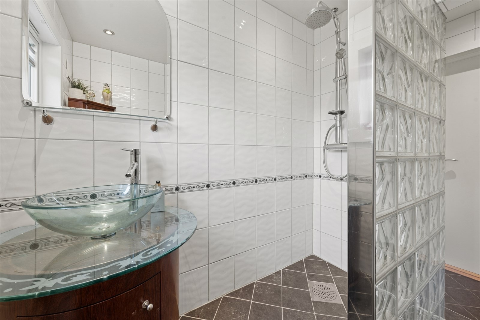 Badet er innredet med gulvstående toalett, dusj direkte på gulv og servantinnredning. Galleribilde