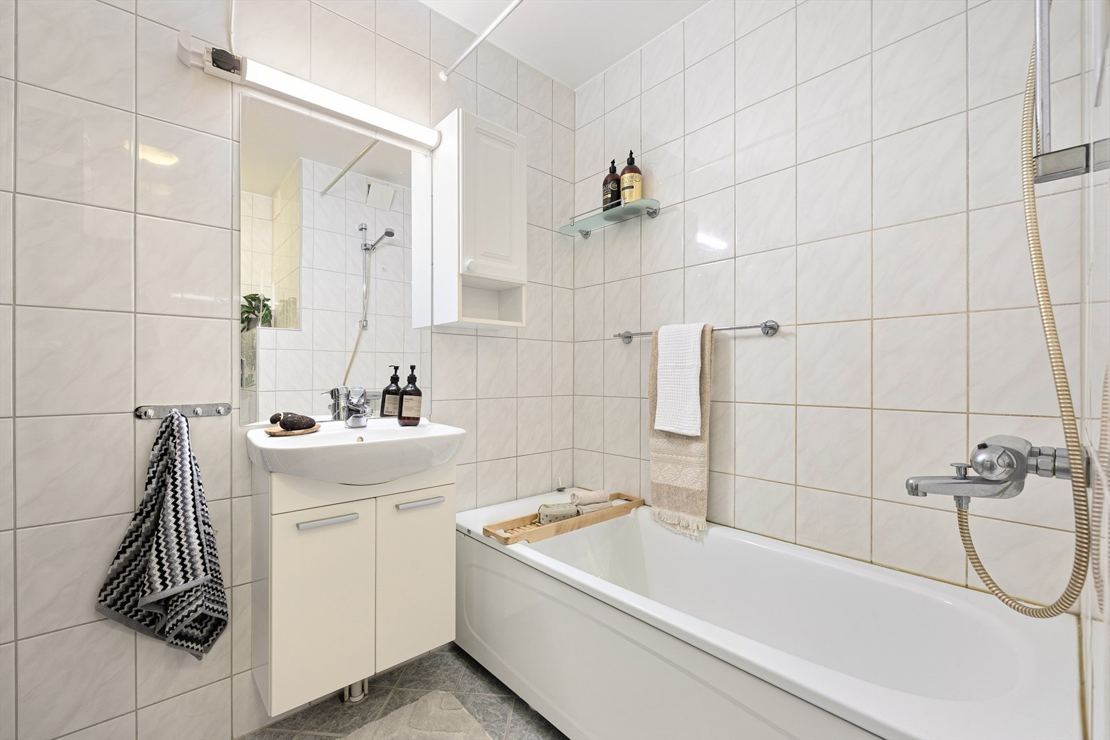 Badet er utstyrt med badekar, naturlig avtrekk, servant, servantskap og veggmontert wc. Galleribilde