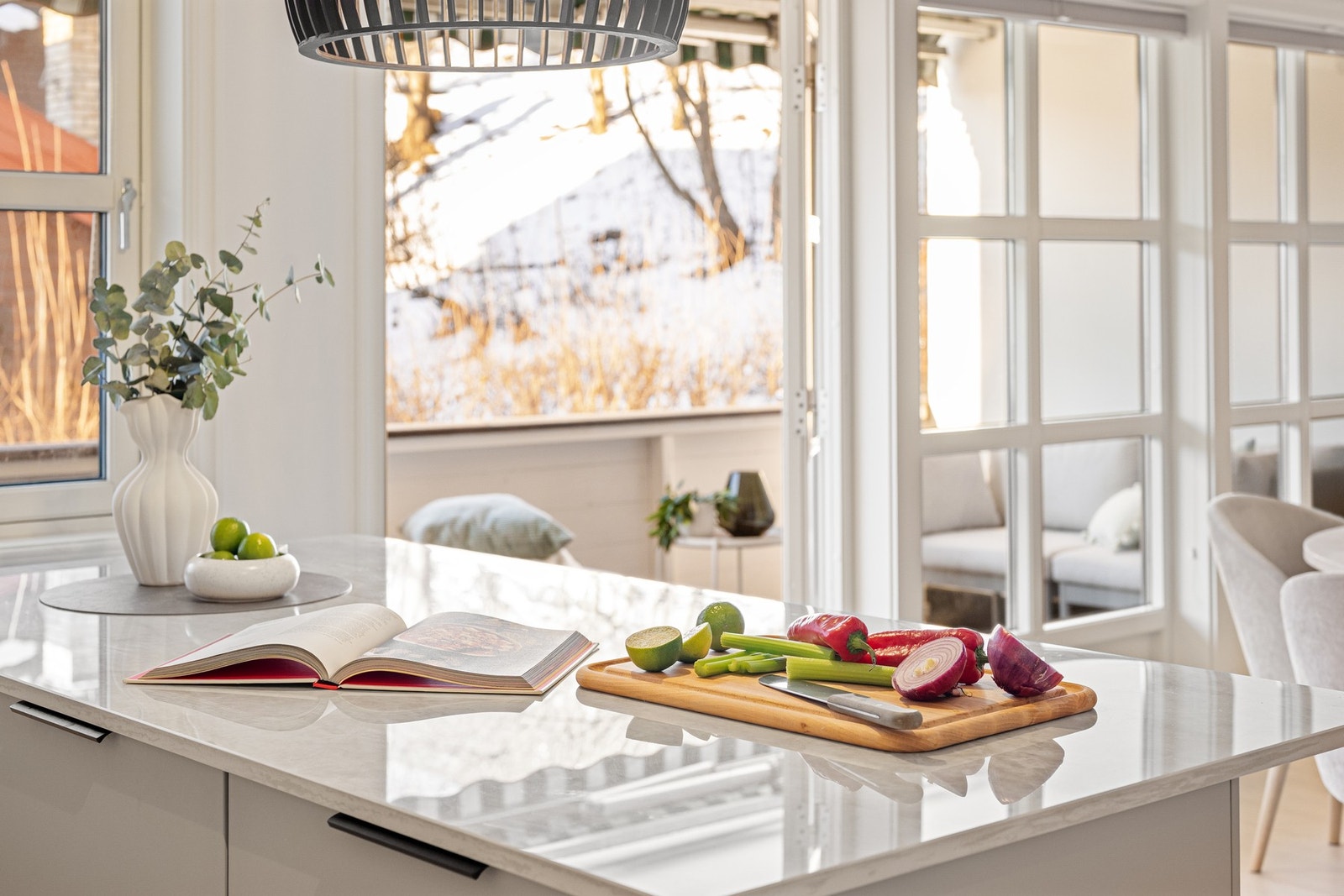 Store vindusflater gir rikelig med naturlig belysning i både kjøkken og stue Galleribilde