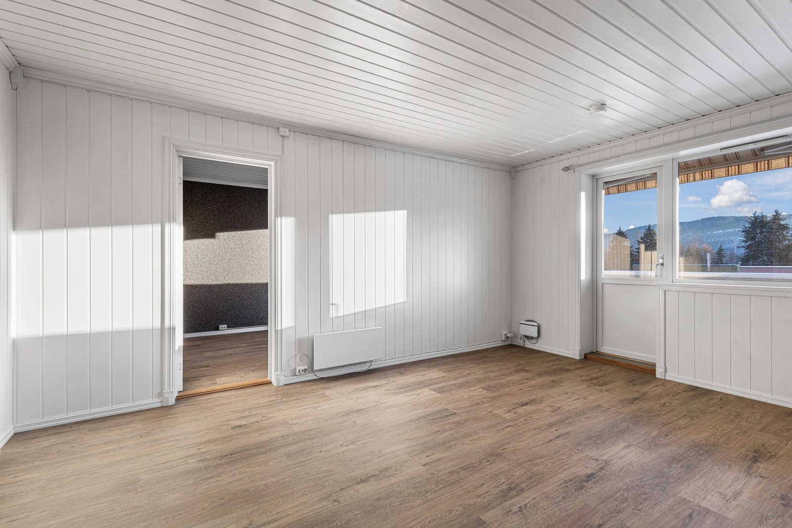 Lys og åpen stue med fin plass for en sofagruppe med tilhørende møblement. Galleribilde