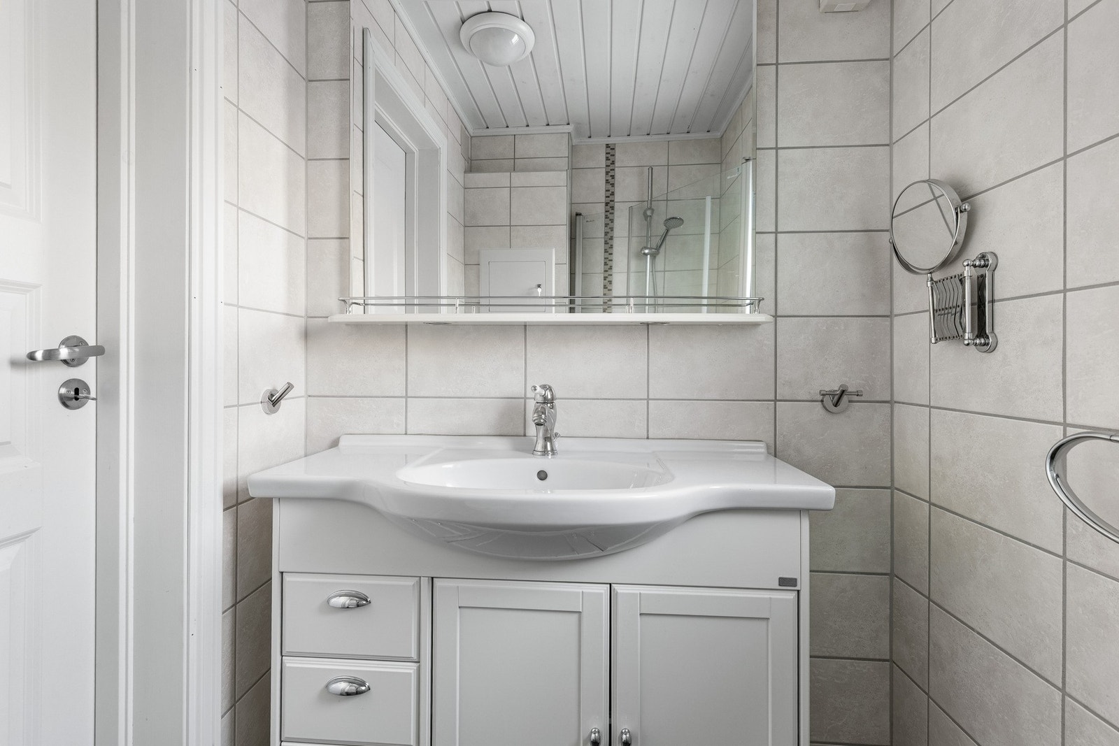 Badet er innredet med servant nedfelt i skapinnredning og speil med lys over. Galleribilde