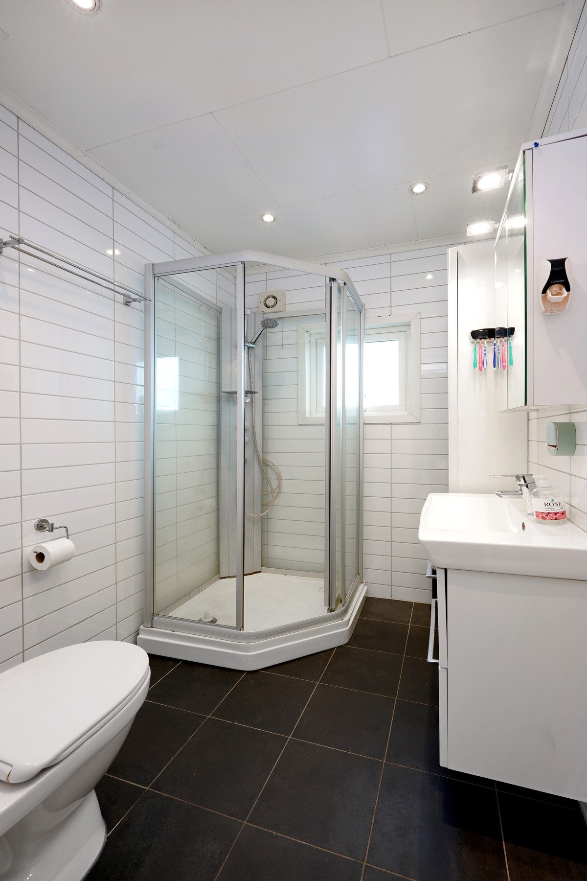 Bad med fliser på gulv, dusjkabinett og servant med underskap. Galleribilde