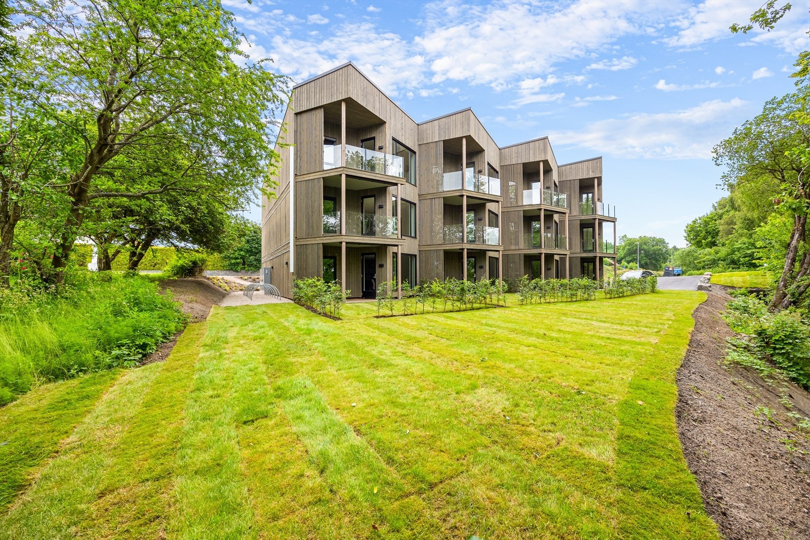 Fellestomten er pent opparbeidet med gressplen, forstøtningsmurer, stensatte områder og asfaltert gårdsplass/ gangveier. Galleribilde