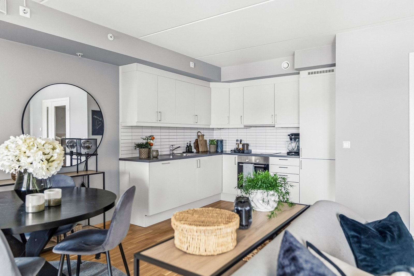 Det er fliser på vegg over benkeskap og laminat benkeplate med nedfelt kum i rustfritt stål. Galleribilde