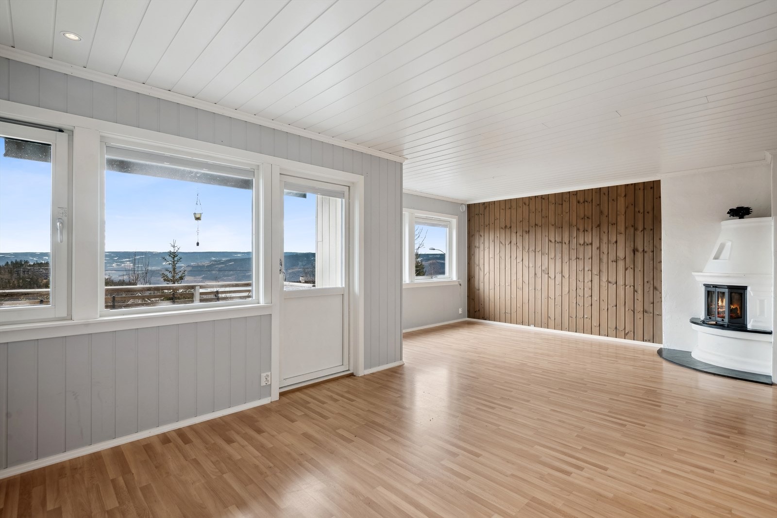 Lys og luftig stue med peis, gjennomgående laminatgul i etasjen og tilgang til balkong. Galleribilde