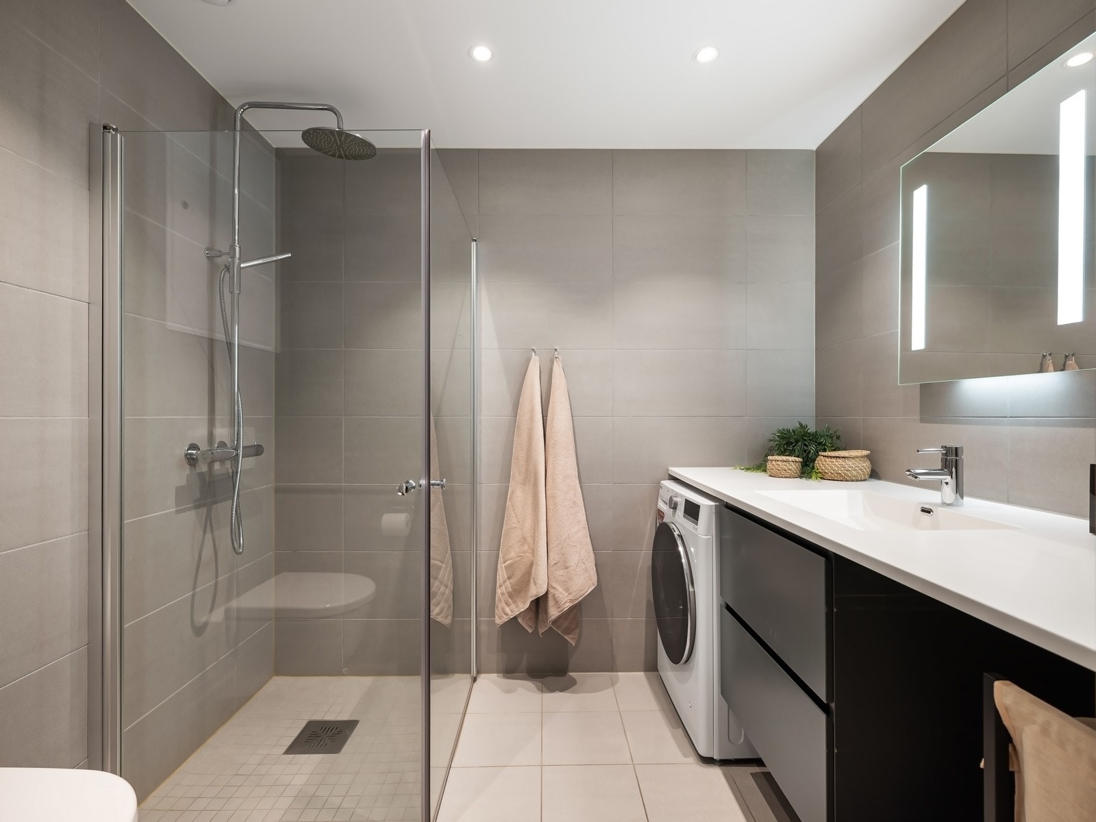 Badet fra 2023 fremstår moderne og stilrent, med flislagte gulv og vegger samt slett himling med downlights. Galleribilde