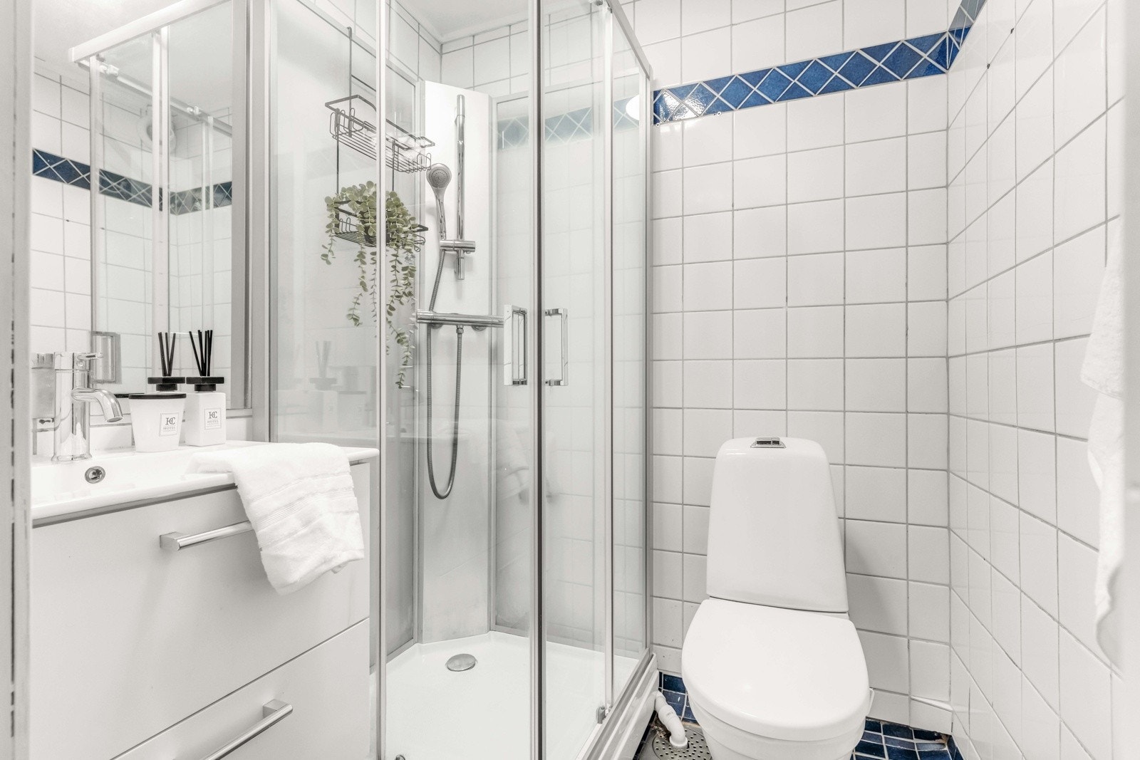 Flislagt bad med dusjkabinett, servant med underskap og toalett. Galleribilde