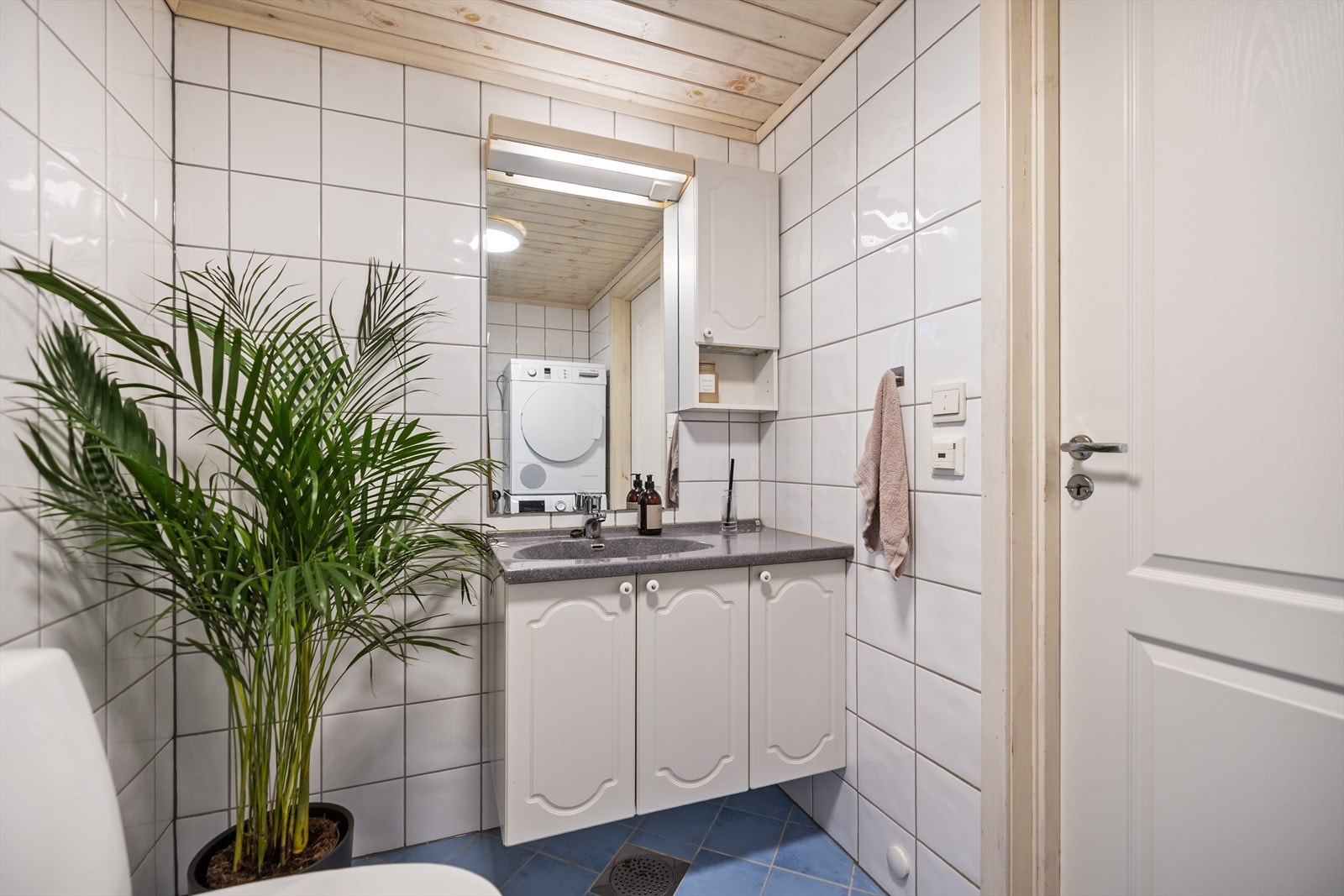 Badet er innredet med dusjhjørne, servant i innredning, toalett og opplegg for vaskemaskin. Galleribilde