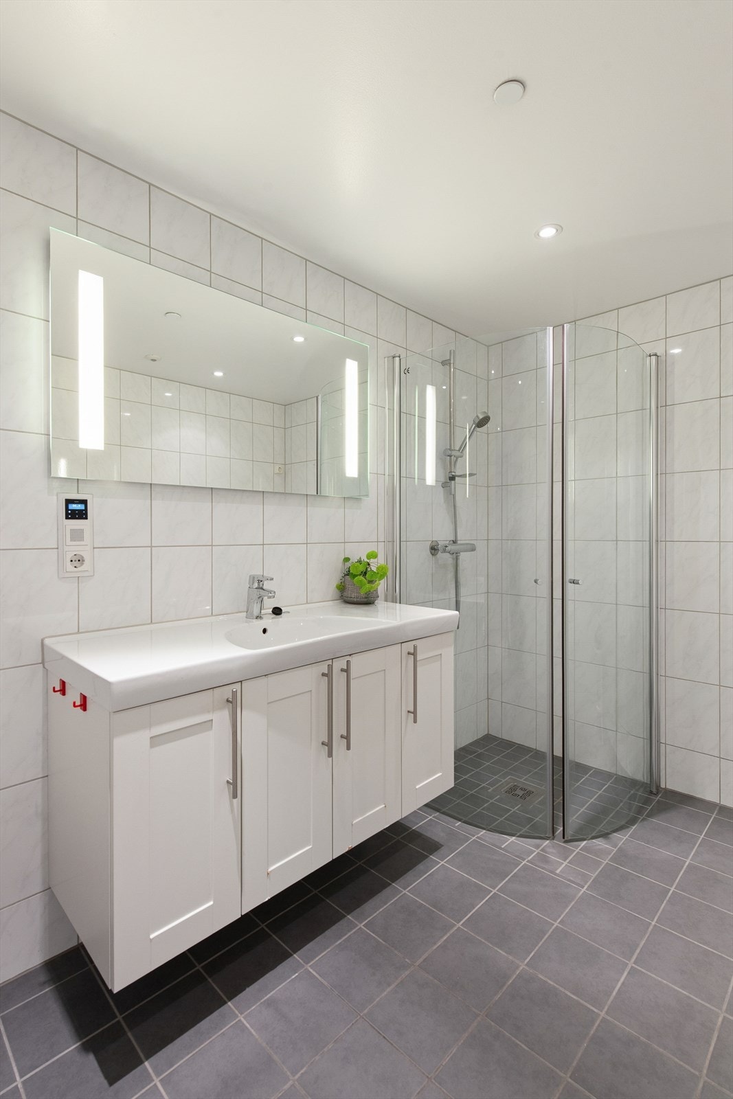 Videre er rommet utstyrt med dusjvegger, vegghengt toalett og opplegg for vaskemaskin. Ventilasjon er balansert, med tilluft via tilstøtende rom. Galleribilde