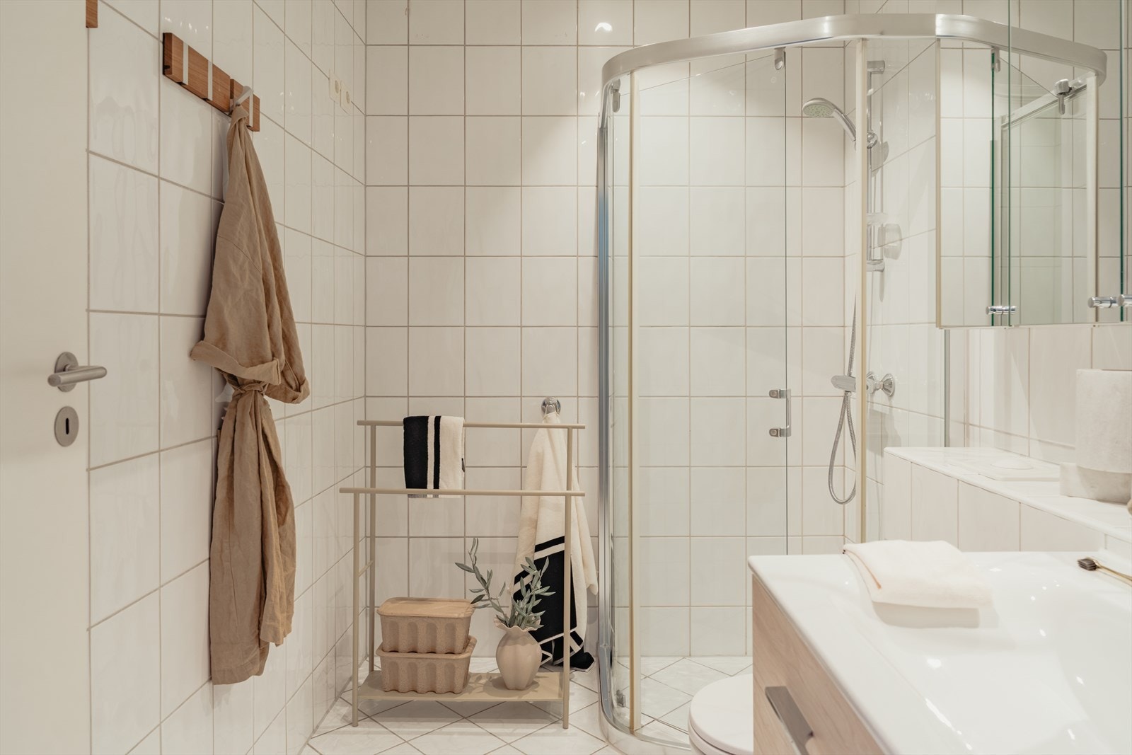 Innredningen består av baderomsinnredning med nedfelt servant, vegghengt toalett, dusjhjørne og opplegg for vaskemaskin Galleribilde