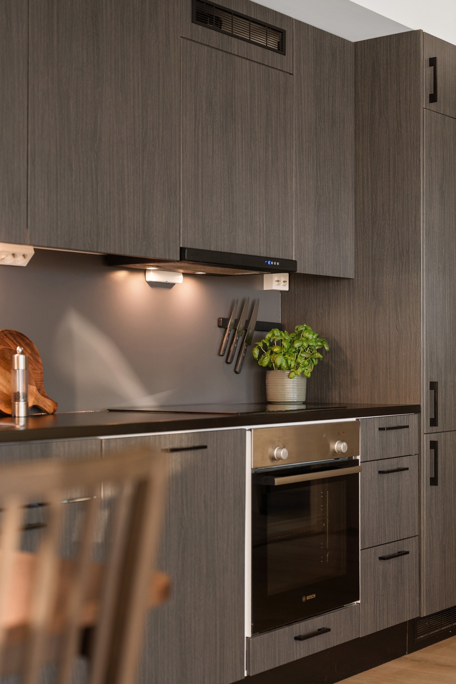 Avtrekk over stekesone og platekledd vegg i sprutsoner over kjøkkenbenk. Galleribilde