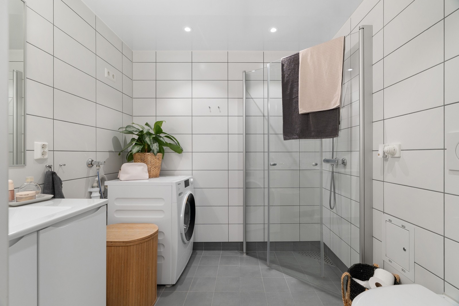 Lekkert og tidløst innredet baderom med flis på gulv og vegg, og downlights i himling. Vegghengt wc og romslig dusjhjørne med innfellbare dusjvegger Galleribilde