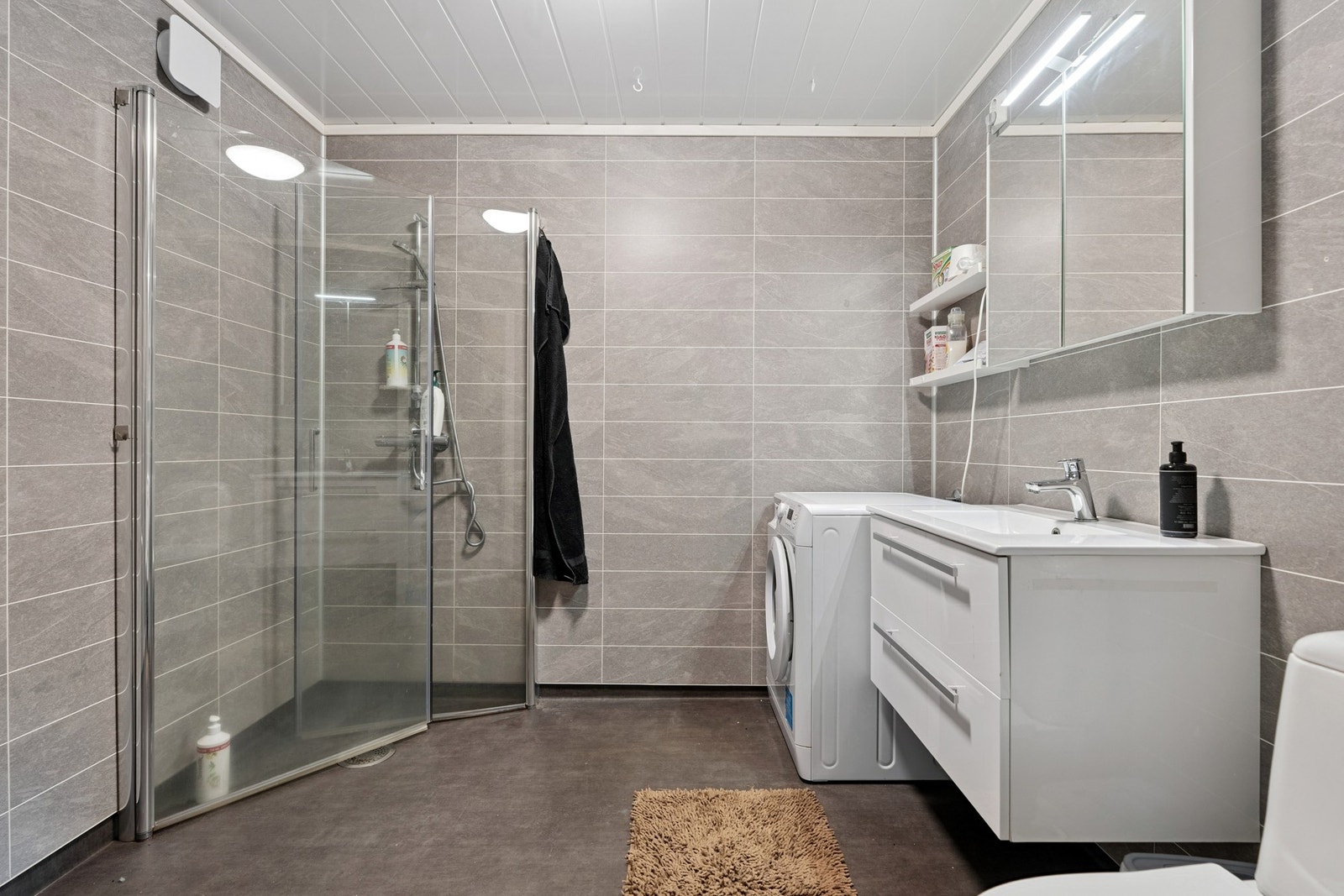 Badet er innredet med heldekkende servant, toalett, dusjhjørne og opplegg for vaskemaskin. Deler av rommet er opprinnelig en bod, søknadspliktig tiltak. Galleribilde