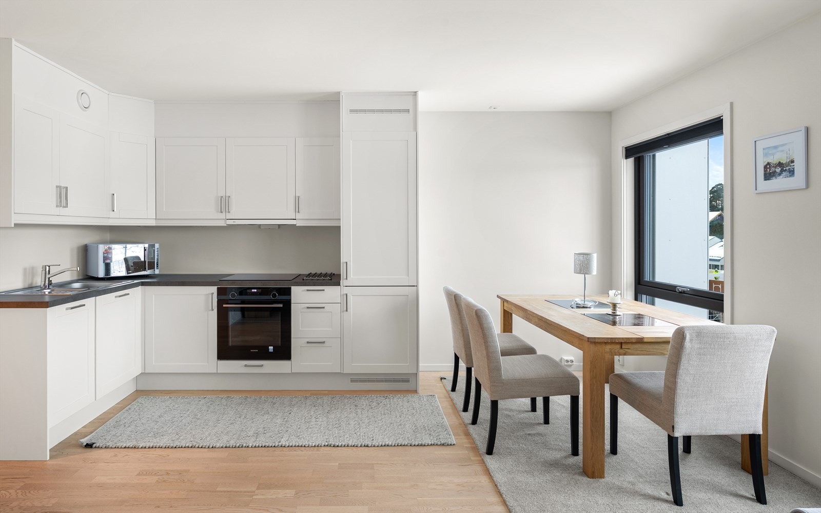 Kjøkkenet har hvit, profilert innredning og mørk benkeplate i slitesterk laminat. Galleribilde