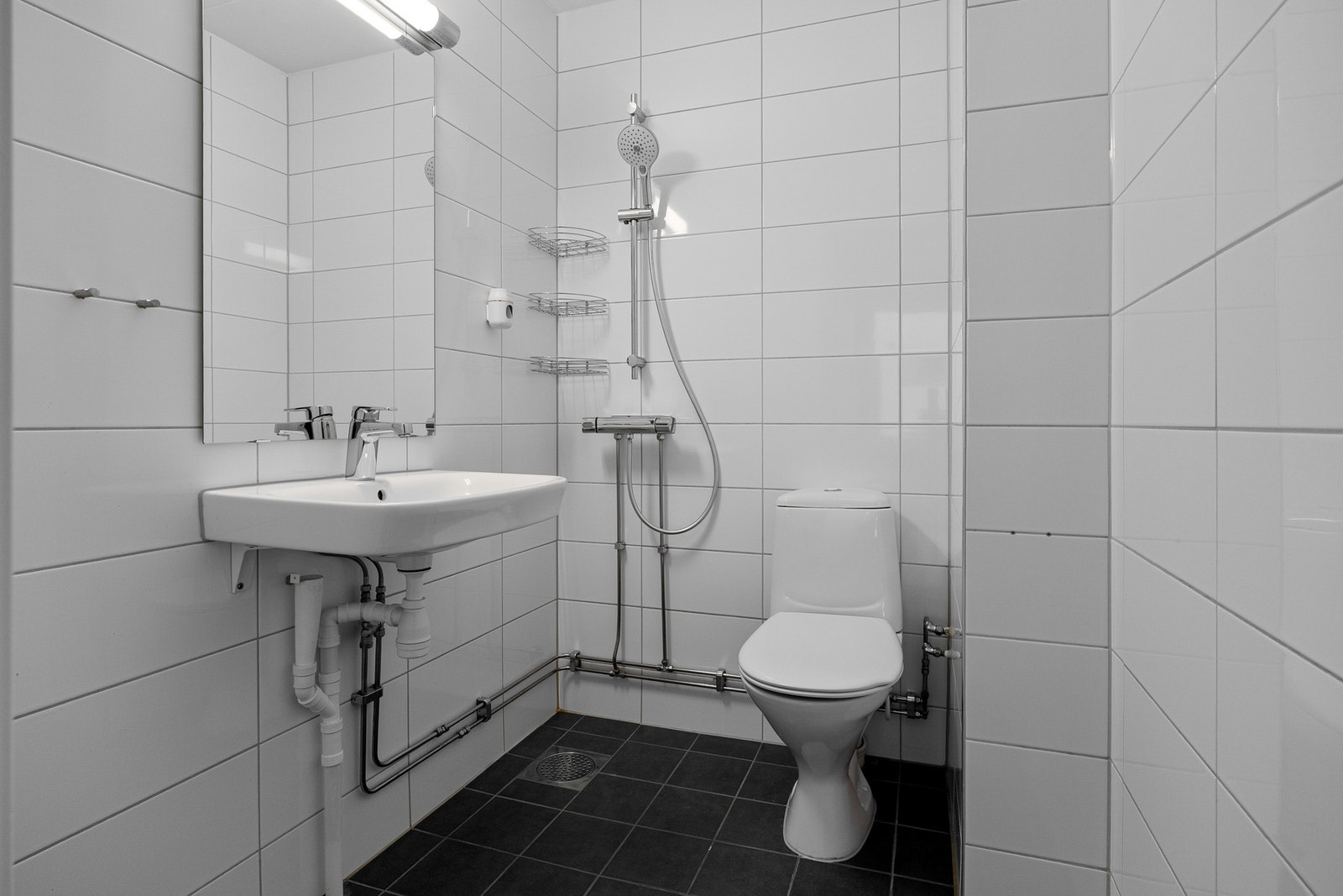 Flislagt bad med dusj, wc, servant og opplegg for vaskemaskin. Galleribilde