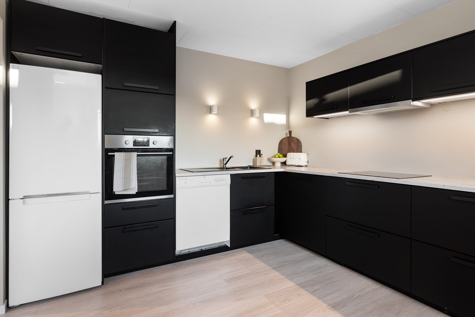 Innredningen har glatte fronter fra IKEA og integrerte hvitevarer, herunder induksjonstopp og stekeovn Galleribilde