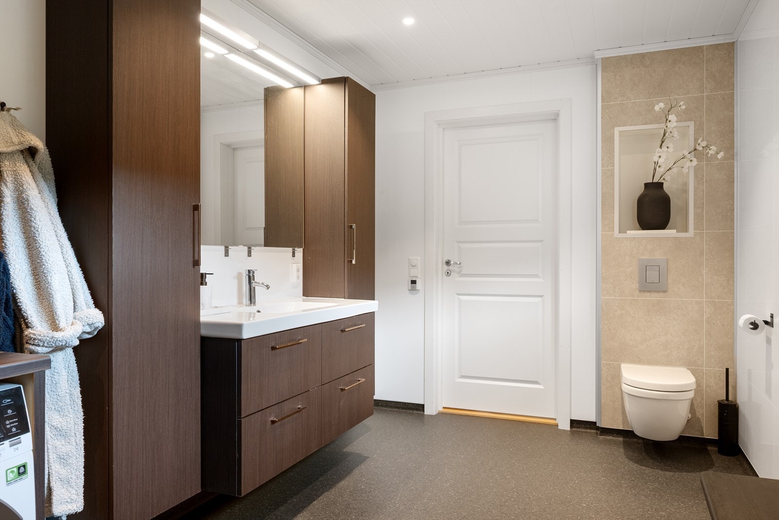 Rommet er innredet med en tidsriktig skuffeinnredning med tilhørende overskap, dusjvegger og vegghengt wc. Galleribilde