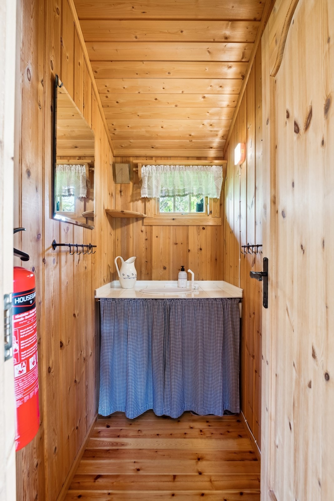 Enkelt sanitærrom med håndvask som har avløp til bøtte. Galleribilde