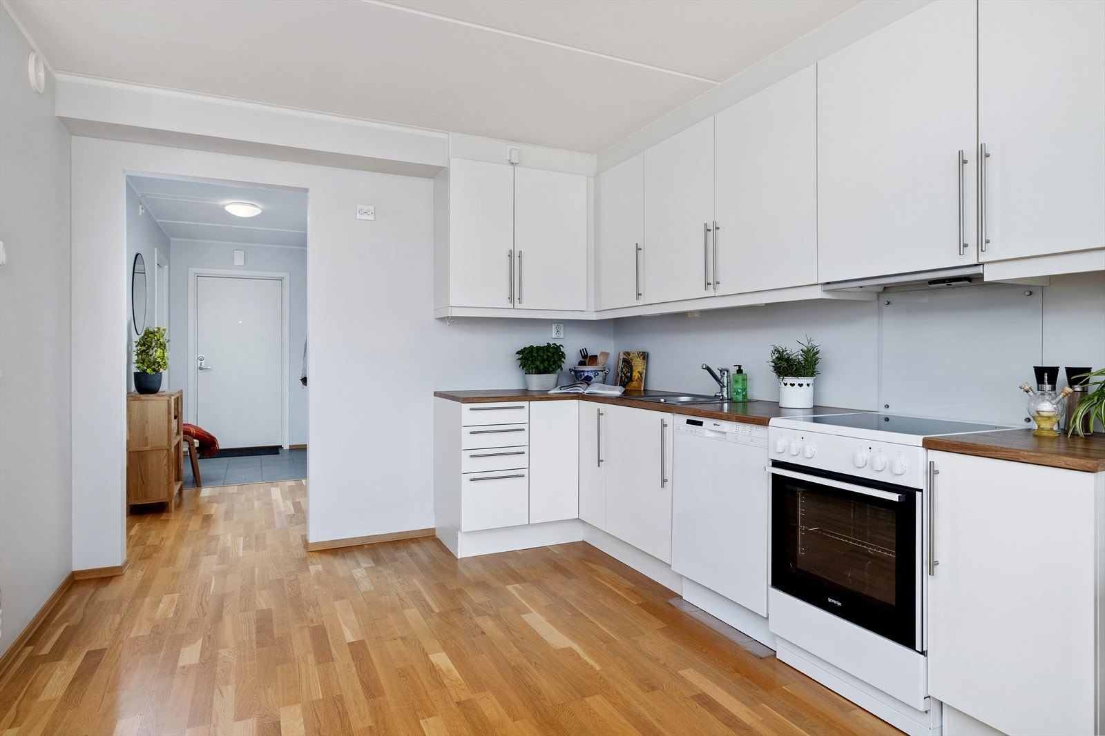 Kjøkkeninnredning med glatte fronter, laminat benkeplate og halvannen kjøkkenkum av stål. Galleribilde