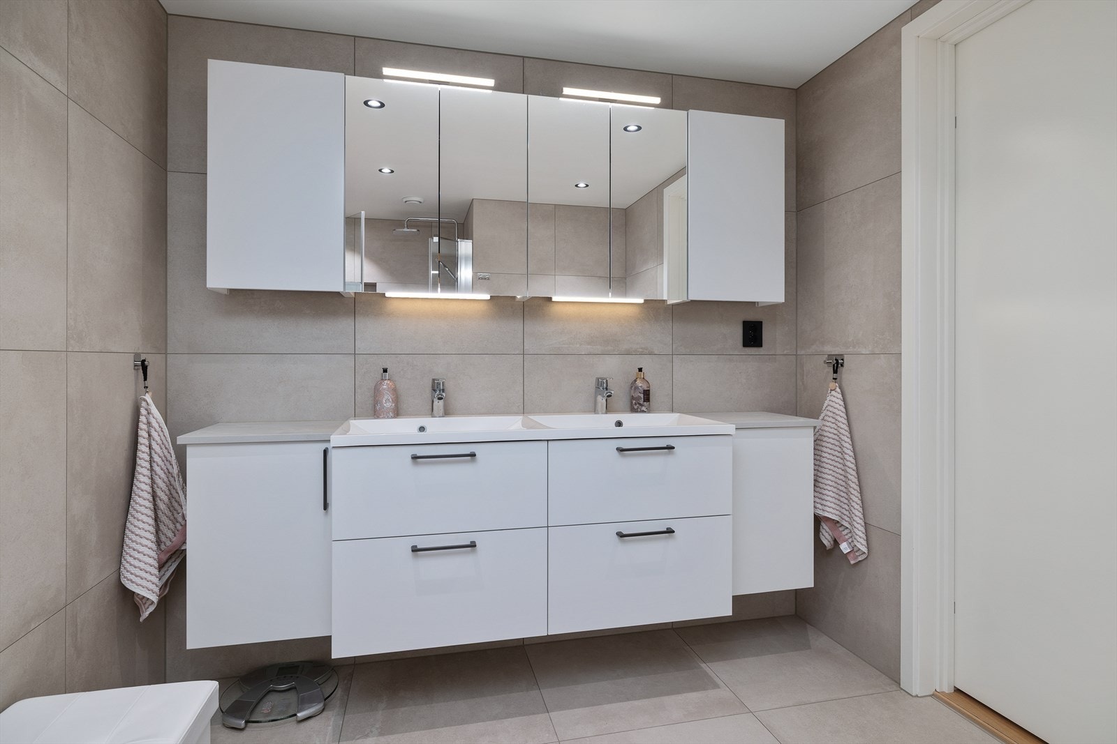 Badet har innredning med 2 nedfelte servanter. Rom for oppbevaring i skuffeseksjon og speil med belysning. Galleribilde