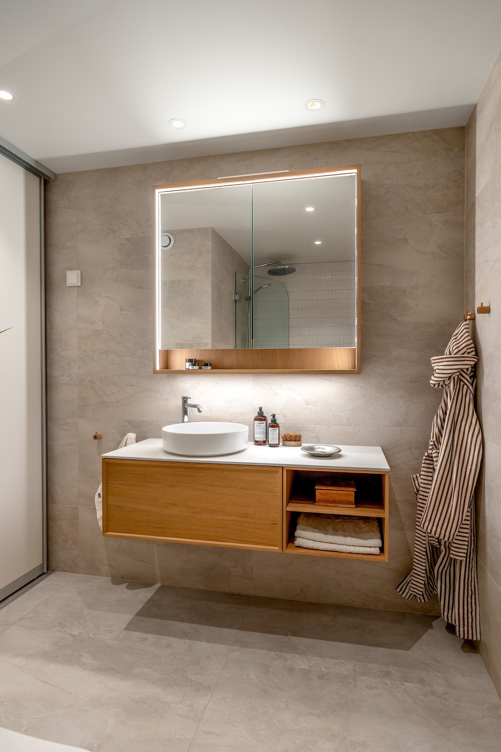 Videre har badet servantskap fra INR med fronter i eik, servantbolle over benkeplate og speilskap med belysning over servant Galleribilde