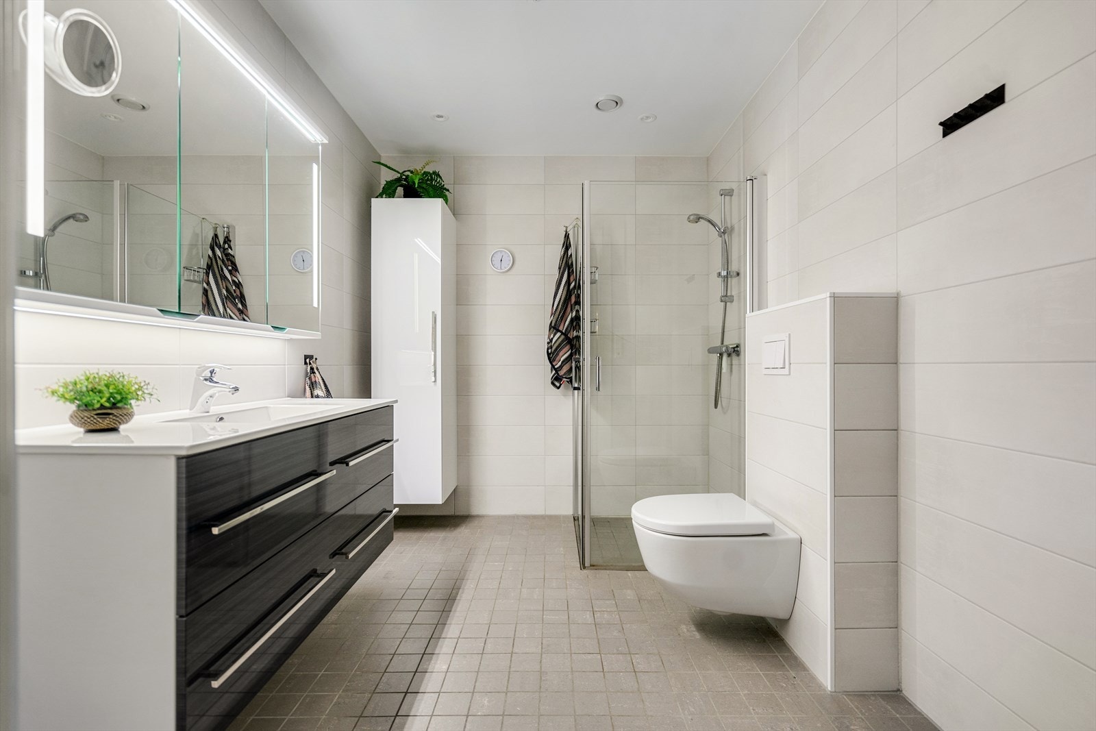 Badet har innredning med heldekkende servant med underskap, speilskap og hjørneskap som gir rikelig med oppbevaring. Galleribilde