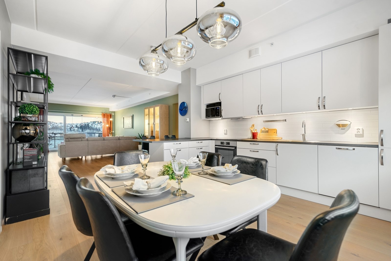 Et innbydende og sosialt hovedrom med gjennomgående lys der kjøkken, spiseplass og stue flyter naturlig sammen. Galleribilde