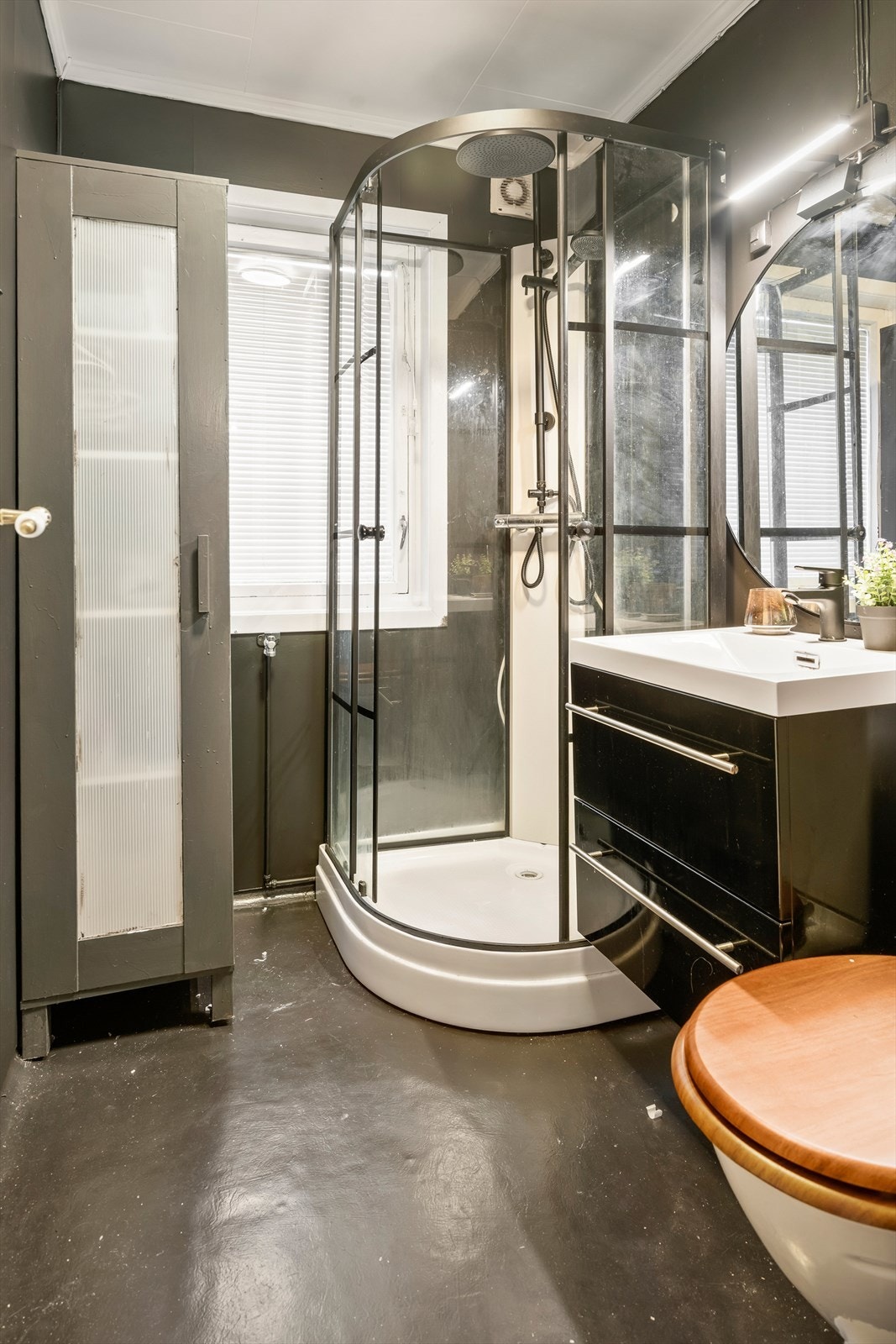 Badet er innredet med en servantinnredning, toalett og et dusjkabinett. Galleribilde