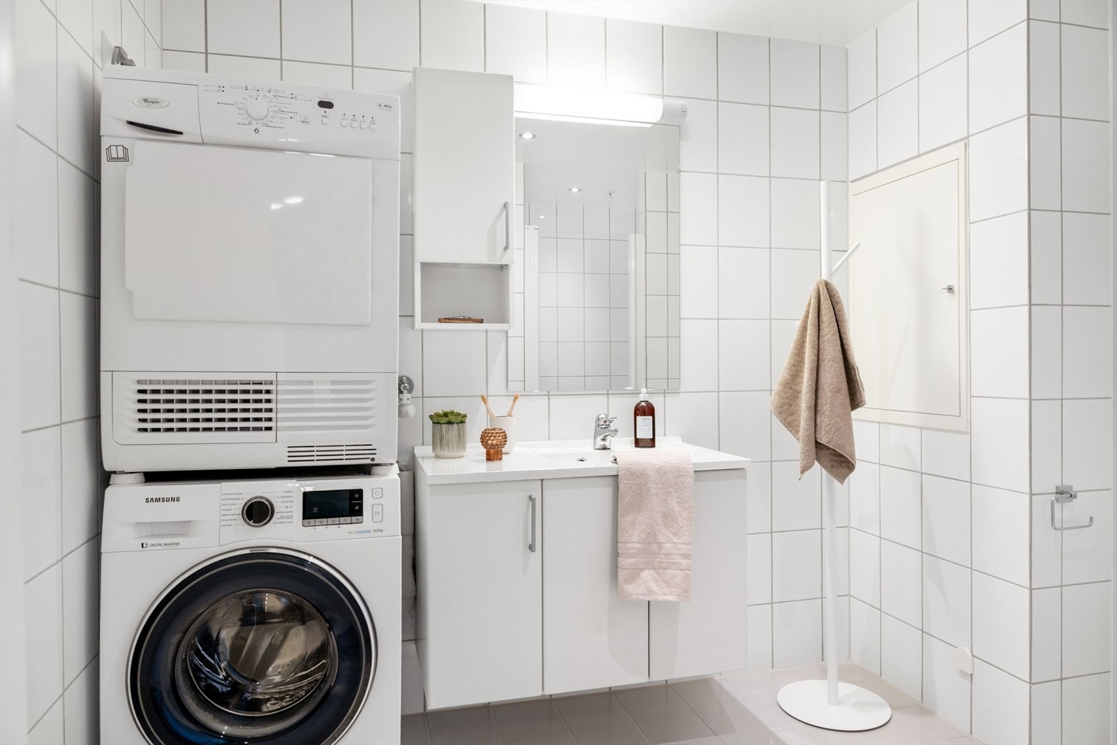 Funksjonelt og tidløst helfliset bad med servant med underskap, speil med belysning, vegghengt toalett og dusjnisje. Galleribilde