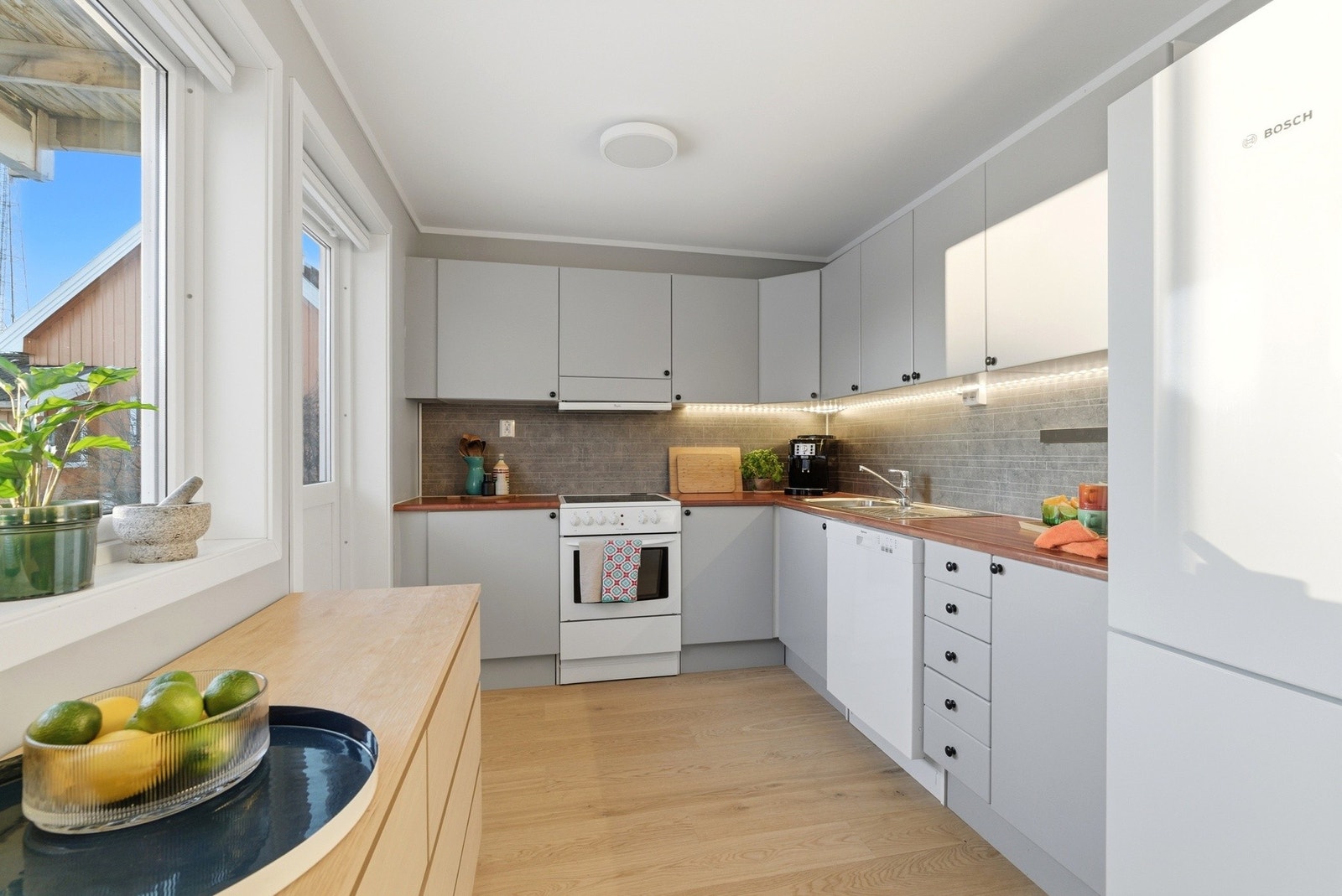 Kjøkkenet er stilrent med lyse fronter og kitchenboard over benk. Galleribilde