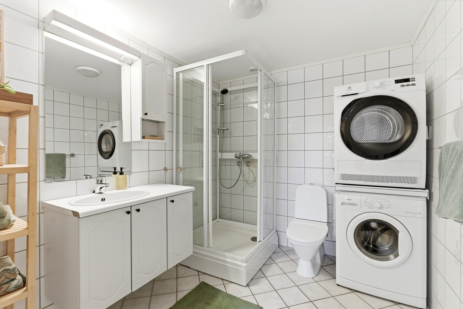 Flislagt bad med varmekabler i gulvet. Rommet har lys innredning, toalett, dusjkabinett og opplegg for vaskemaskin. Galleribilde