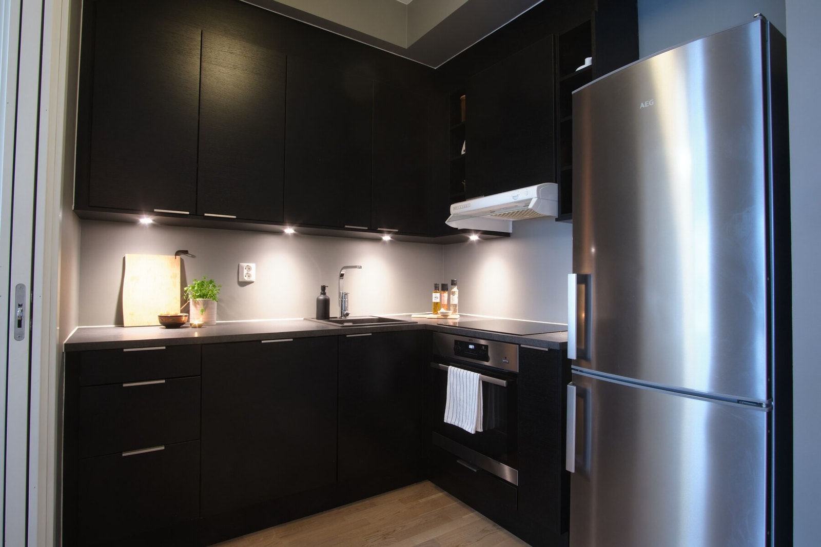 Integrerte hvitevarer som induksjonsplatetopp, stekeovn, oppvaskmaskin og frittstående kjøl/frys. Kjøkkenvifte fører matos ut av rommet i kanal Galleribilde