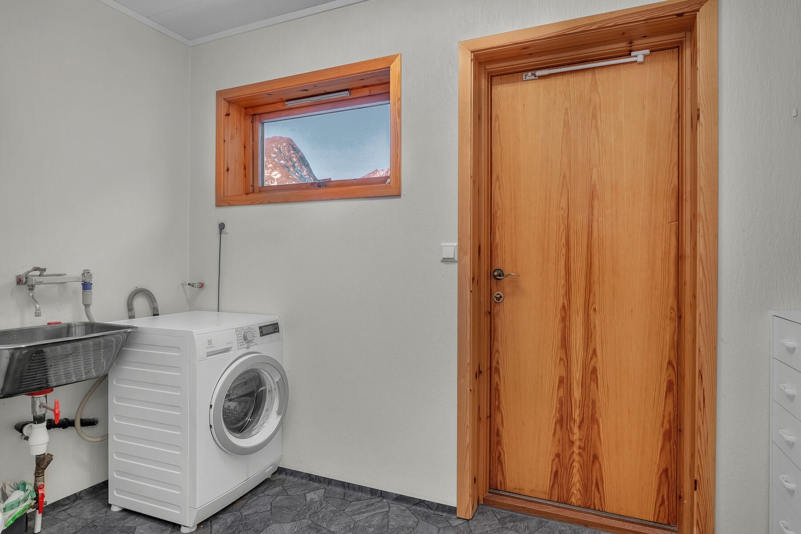 Separat vaskerom med opplegg for vaskemaskin og skyllekar i stål. Herfra er det egen utgang til uteområdet. Galleribilde