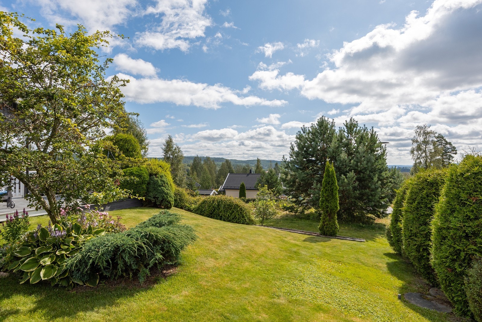 Tomten er meget pent opparbeidet med gressplen, frodige prydbusker, velfrisert hekk og gruslagt gårdsplass, og det er rikelig med trygg boltreplass i en stor, solrik hage. Galleribilde